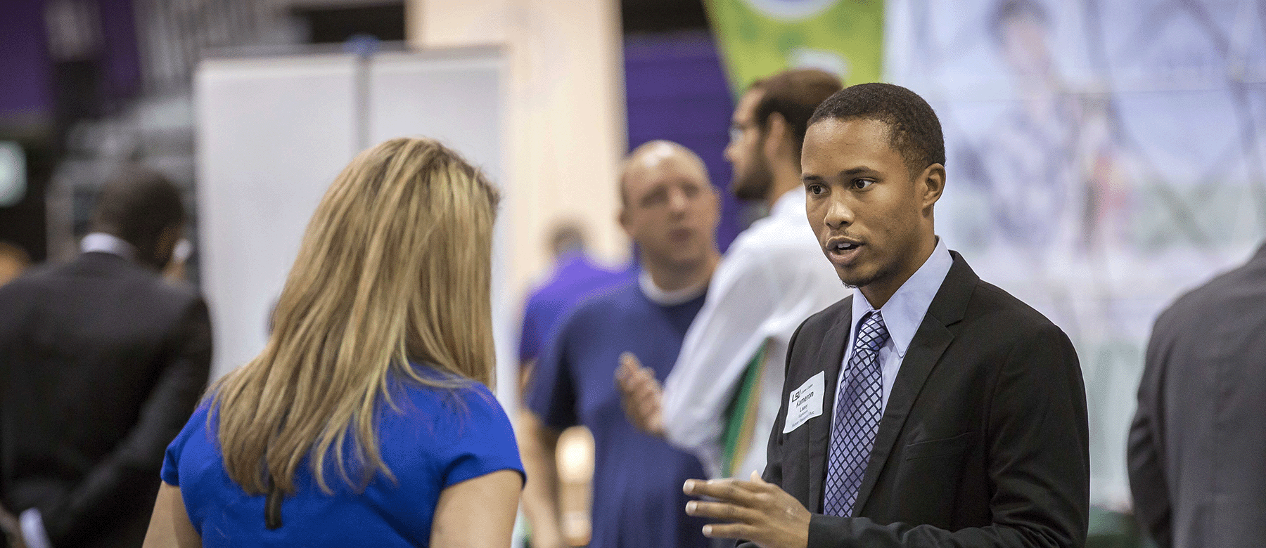 A male student speaks with a recruiter at a career event.